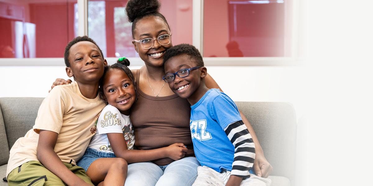 a mother and her three kids sit on a couch