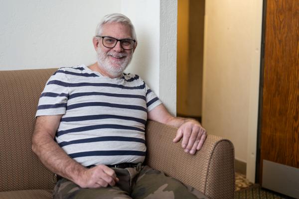 a man sits on a couch, smiling