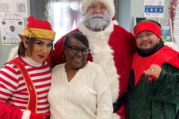 four people stand together, smiling at the camera